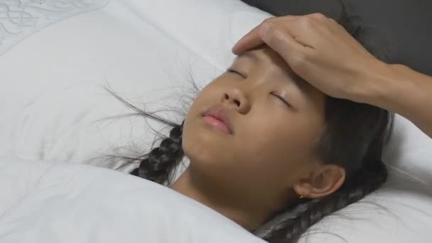 Asian child sick and sleeping on the bed with her mother by her side. - Filmagem, Vídeo