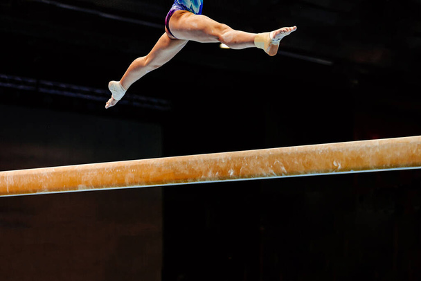 pernas mulher exercício split jump no equilíbrio feixe ginástica em fundo preto - Foto, Imagem