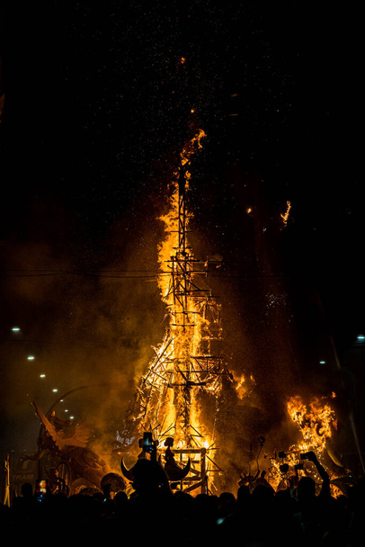 Verticaal beeld van een houten constructie in vlammen tijdens de viering van St. John 's Eve, 24 juni, waar ze de figuren van de kampvuren verbranden. - Foto, afbeelding