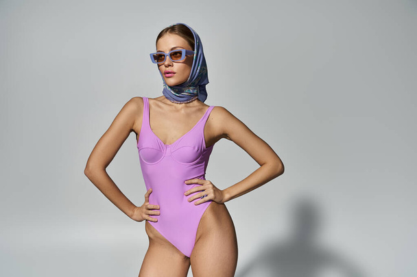 Femme blonde élégante frappe une pose en maillot de bain violet. - Photo, image