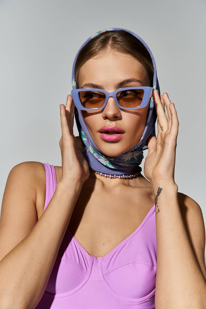 Stijlvolle vrouw straalt vertrouwen in zonnebril en hoofddoek. - Foto, afbeelding