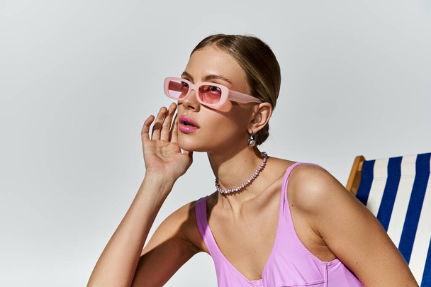 Блондинка розслабляється на пляжному стільці в модних рожевих сонцезахисних окулярах. - Фото, зображення