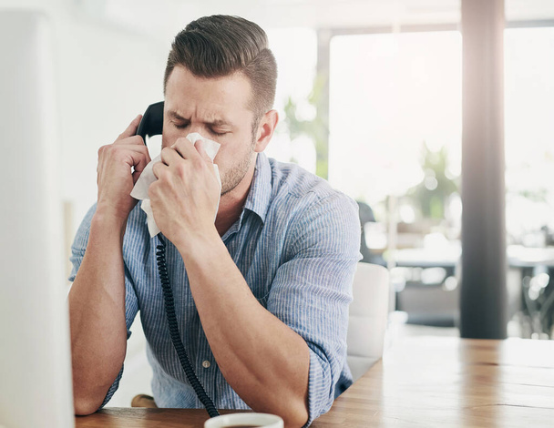 Businessman, sick and blowing nose on phone call in office with allergy, virus or tissue for healthcare at desk. Employee, medical illness or tired of hayfever with cleaning mucus from sneeze or flu. - Photo, Image