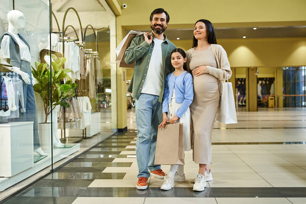 Una mujer embarazada y su hija navegan felices y compran juntas en un centro comercial durante una excursión familiar. - Foto, imagen
