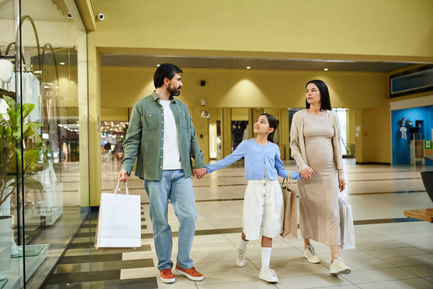Радісна сім'я прогулюється по галасливому торговому центру, несучи різнокольорові сумки, наповнені своїми вихідними знахідками. - Фото, зображення