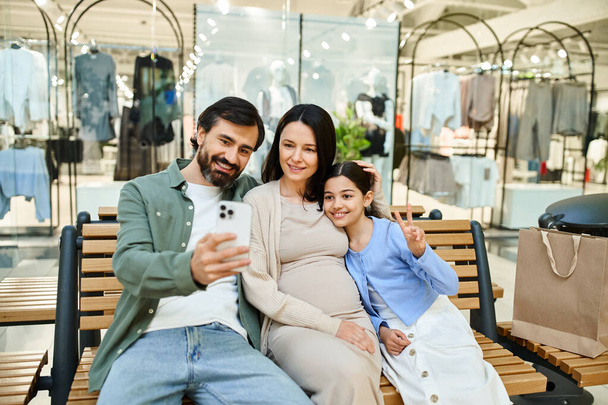 Una famiglia gioiosa cattura un momento su una panchina in un centro commerciale, sorridendo mentre si fanno un selfie insieme. - Foto, immagini