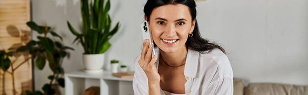 Kobieta w luźnym stroju rozmawia przez telefon podczas pracy w domu. - Zdjęcie, obraz