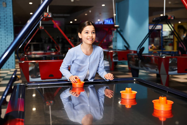Ein junges Mädchen spielt energisch Airhockey in einem Einkaufszentrum - Foto, Bild