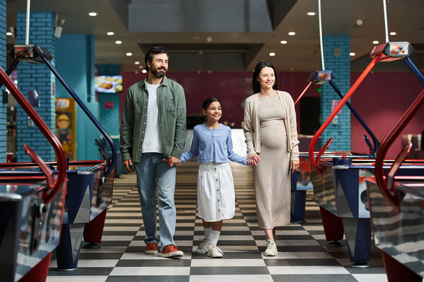 Щаслива сім'я радісно прогулюється через повітряний хокей у торговому центрі у вихідні, насолоджуючись разом днем розваг.. - Фото, зображення