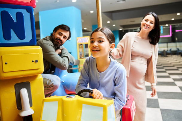 Eine schwangere Frau und ihre Tochter lachen und spielen während eines lustigen Wochenendausflugs in einem Einkaufszentrum. - Foto, Bild