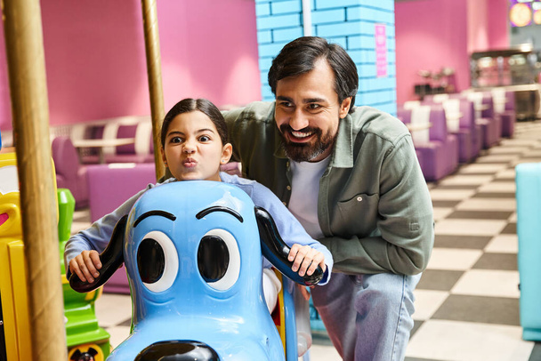 vader en kind rijden vrolijk op een kleurrijke draaimolen in een speelgoedwinkel, omringd door andere gelukkige gezinnen in een winkelcentrum. - Foto, afbeelding