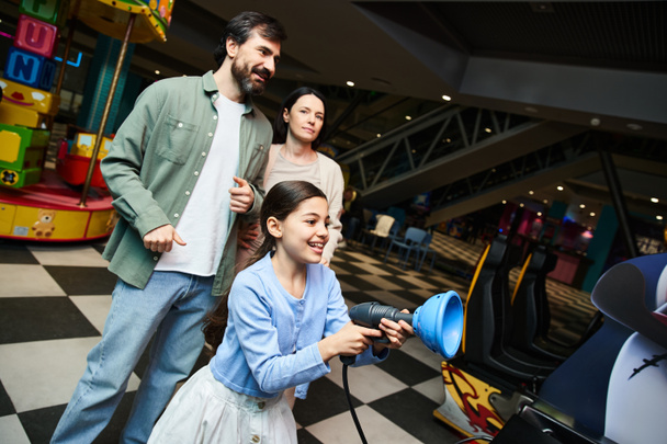 Una familia feliz jugando un juego en un arcade, compartiendo risas y emoción durante su excursión de fin de semana. - Foto, imagen