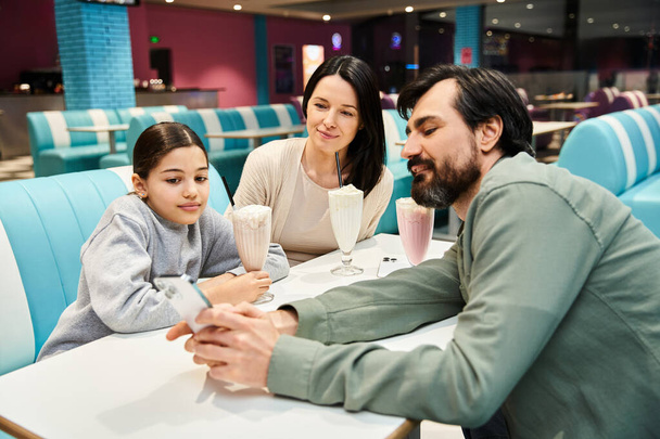A cheerful family enjoys a meal together in a stylish restaurant, creating lasting memories of togetherness and joy. - Photo, Image