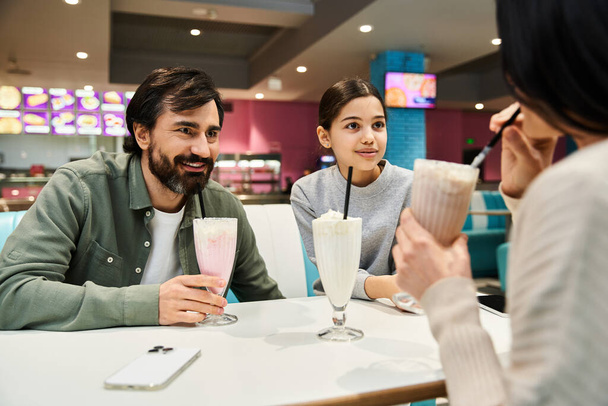 Una familia feliz disfrutando de un tiempo de calidad juntos en un restaurante moderno, vinculándose con bebidas y conversaciones animadas. - Foto, imagen