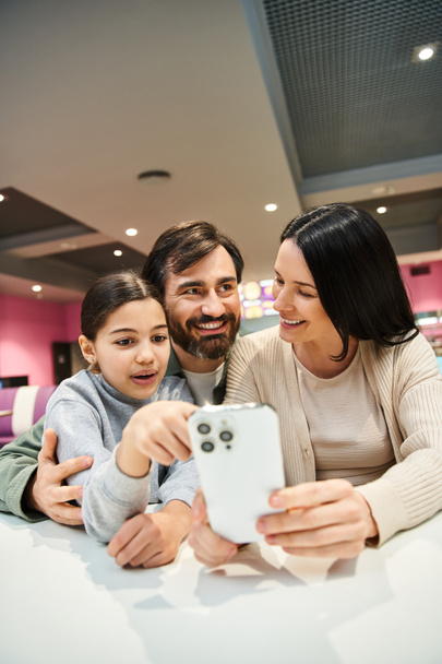 Een gelukkig gezin lacht en poseert voor een foto met hun mobiele telefoon tijdens een weekend uitje. - Foto, afbeelding