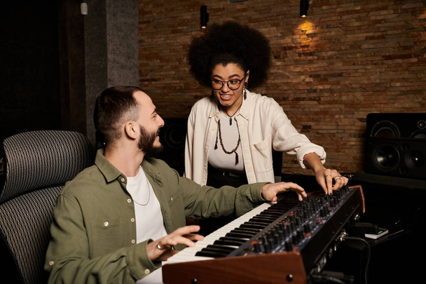 Ένας άντρας και μια γυναίκα συνεργάζονται σε ένα στούντιο ηχογράφησης, αφοσιωμένοι στη δημιουργία μουσικής για την πρόβα της μπάντας τους.. - Φωτογραφία, εικόνα