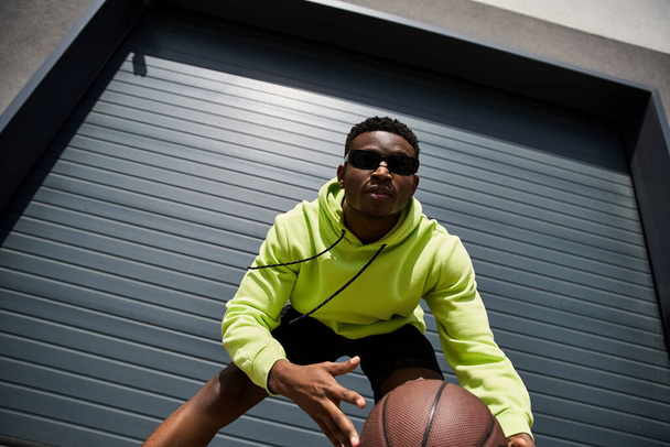 Bello uomo afroamericano con cappuccio verde che tiene il basket. - Foto, immagini