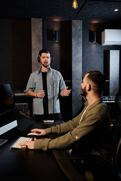 Dva muži v nahrávacím studiu se zapojují do animované diskuze při zkoušce hudební kapely. - Fotografie, Obrázek