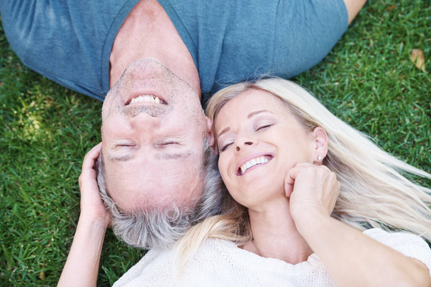 Starší, šťastný pár a venkovní odpočinek na trávě shora k výročí sňatku, cestování nebo vztahu. Muž, žena a pohled shora v zahradním parku na Novém Zélandu na dovolenou výlet, klid nebo příroda. - Fotografie, Obrázek