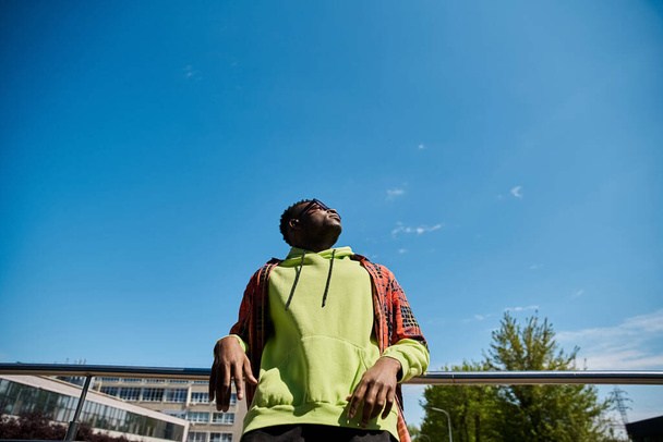 スタイリッシュなアフリカ系アメリカ人男性が空を見上げる. - 写真・画像