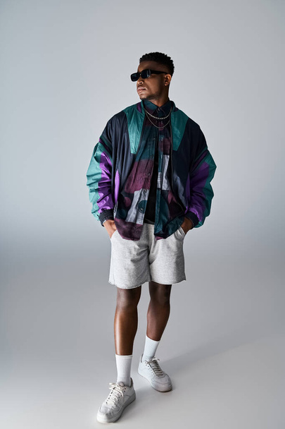 Стильный афроамериканец в красочной куртке и шортах уверенно позирует. - Фото, изображение