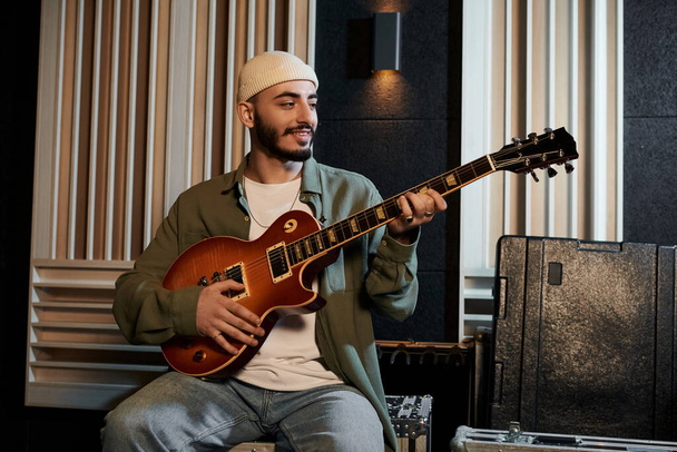 Un musicista strumenta una chitarra in uno studio di registrazione durante le prove di una band musicale. - Foto, immagini