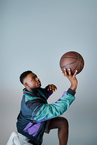 Een stijlvolle Afro-Amerikaanse man vangt een basketbal met vaardigheid en precisie. - Foto, afbeelding