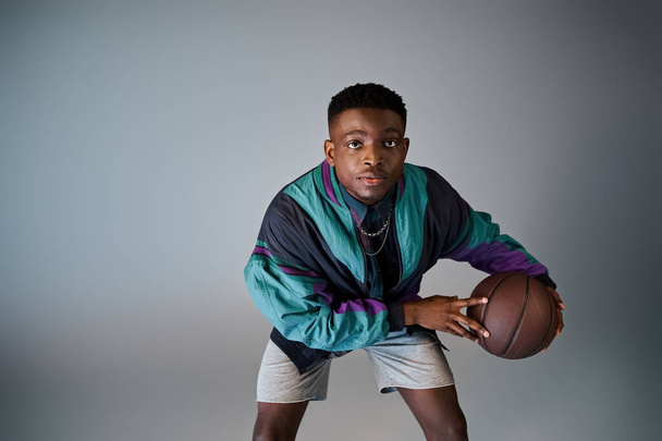 Красивый афроамериканец в стильной одежде держит баскетбольный мяч. - Фото, изображение