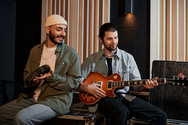 Двое мужчин страстно играют на гитаре в студии звукозаписи во время репетиции музыкальной группы. - Фото, изображение