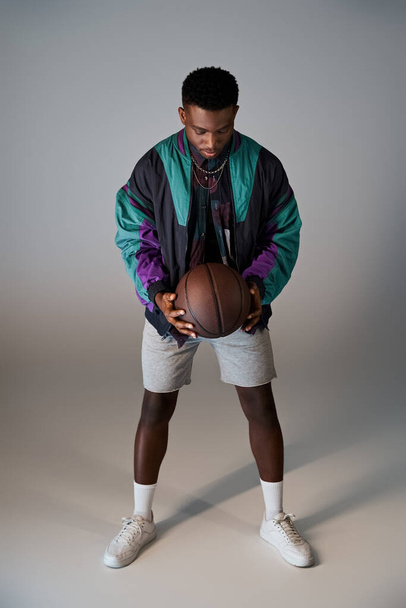 白い背景の前にバスケットボールを保持するファッショナブルな若い男. - 写真・画像