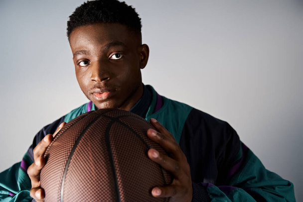 Handsome African American man in trendy attire holding up a basketball ball. - Photo, Image