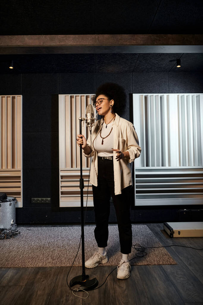 Kobieta pewnie stoi w studiu nagraniowym, gotowa do śpiewania do mikrofonu podczas próby zespołu muzycznego. - Zdjęcie, obraz