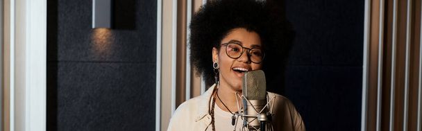 Nainen laulaa intohimoisesti mikrofoniin ammattimaisessa äänitysstudiossa musiikkibändin harjoituksissa.. - Valokuva, kuva