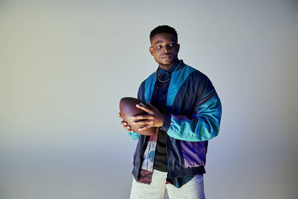Uomo afroamericano in abiti alla moda che tiene un calcio. - Foto, immagini