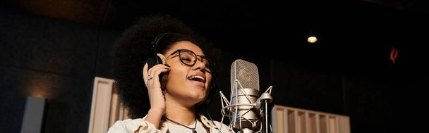 Wokalistka śpiewa namiętnie do mikrofonu w profesjonalnym studiu nagraniowym podczas próby zespołu muzycznego. - Zdjęcie, obraz