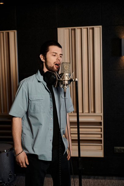 Talentovaný muž vášnivě zpívá do mikrofonu v profesionálním nahrávacím studiu při zkoušce kapely. - Fotografie, Obrázek
