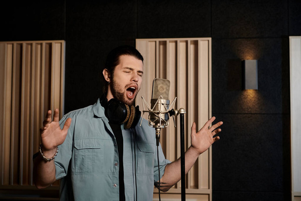 Een man zingt hartstochtelijk in een microfoon in een opnamestudio tijdens een muziekbandrepetitie. - Foto, afbeelding
