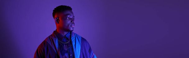 Schöner afroamerikanischer Mann, der selbstbewusst vor einer leuchtend violetten Kulisse steht. - Foto, Bild