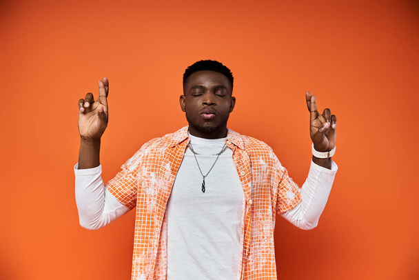 Handsome African American man in stylish orange shirt gestures passionately. - Photo, Image
