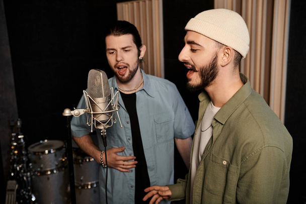 Dois homens compartilham uma performance apaixonada, cantando em um microfone durante um ensaio da banda de música em um estúdio de gravação. - Foto, Imagem