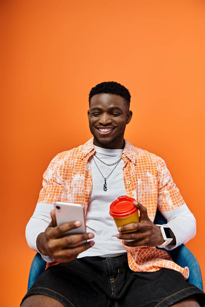 Красивый афроамериканец сидит с кофе и телефоном. - Фото, изображение