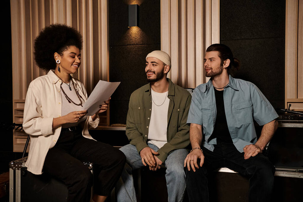Τρία άτομα από ένα μουσικό συγκρότημα κάθονται σε ένα στούντιο ηχογράφησης, ασχολούνται με συζητήσεις και σχεδιάζουν την επόμενη μουσική τους προσπάθεια.. - Φωτογραφία, εικόνα