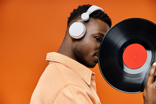 Stylish African American man with headphones holding vinyl record. - Photo, Image