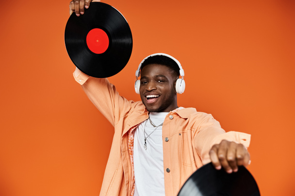 Young black man in stylish attire holding up a vinyl record. - Photo, Image