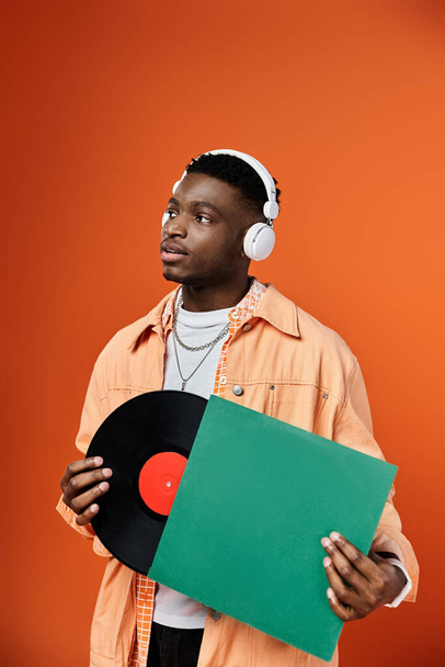 Homme afro-américain élégant avec écouteurs tenant un disque vinyle. - Photo, image