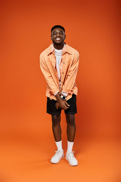 Stilvoller junger Mann in orangefarbenem Hemd und kurzer Hose posiert. - Foto, Bild