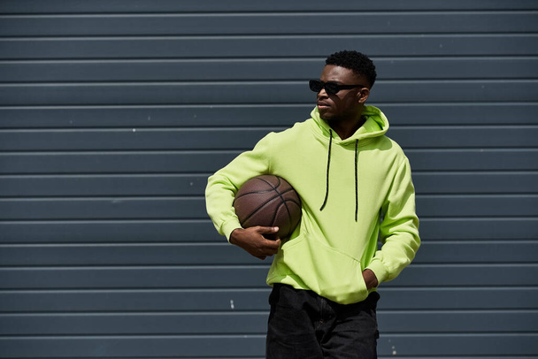 Africano homem americano com capuz verde segurando basquete. - Foto, Imagem