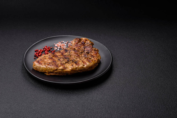 Finom szaftos sertéshús sóval, fűszerekkel és fűszernövényekkel sötét beton alapon - Fotó, kép