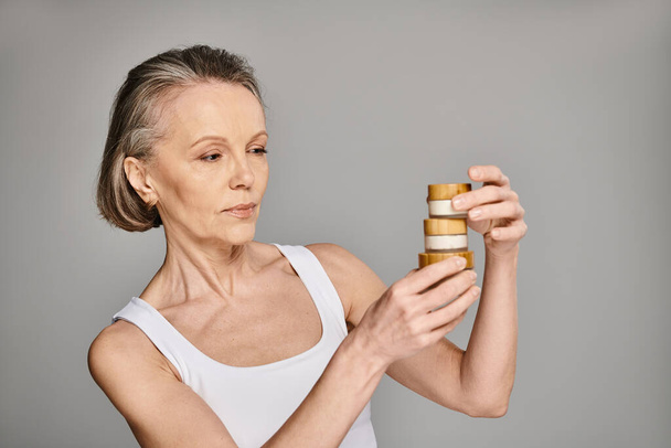 A woman gazes upon a tall stack of cream jars. - Photo, Image