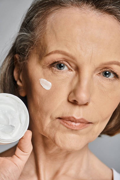 Una donna applica la crema sul suo viso con cura e attenzione. - Foto, immagini